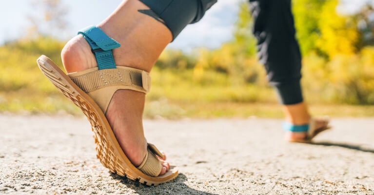 Close up of person wearing Xero trail sandal on a hiking trail.