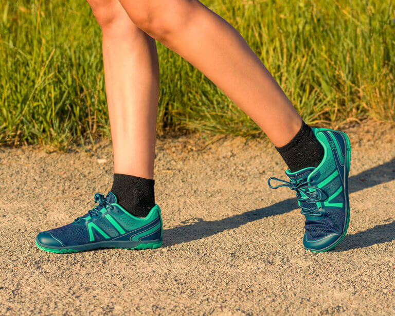 A close up shot of a woman walking in her HFS II barefoot shoes on a dirt road