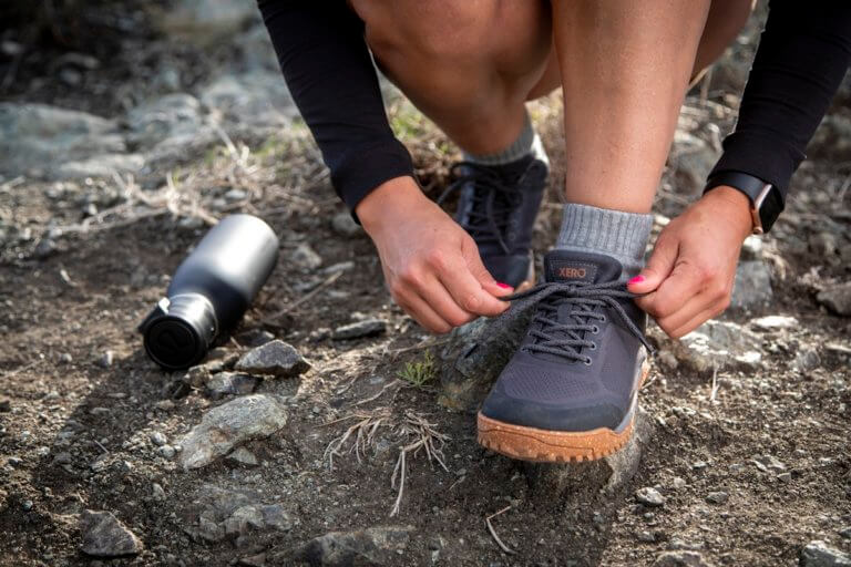 Een vrouw knoopt haar Ridgeway Mesh Low schoenen vast tijdens het wandelen