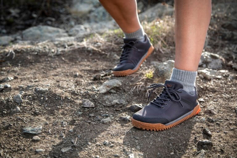 Une femme randonne avec ses chaussures Ridgeway Mesh Low sur un sentier caillouteux.