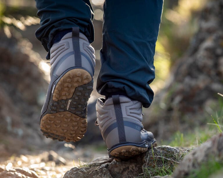 A close up shot of a man walking along a rocky trail in his Scrambler Mid II boots