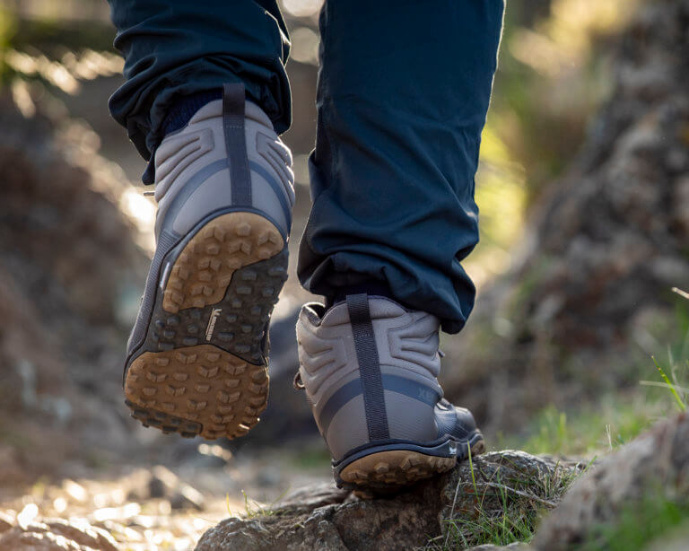 Gros plan sur un homme marchant sur un sentier rocailleux avec ses bottes Scrambler Mid II.