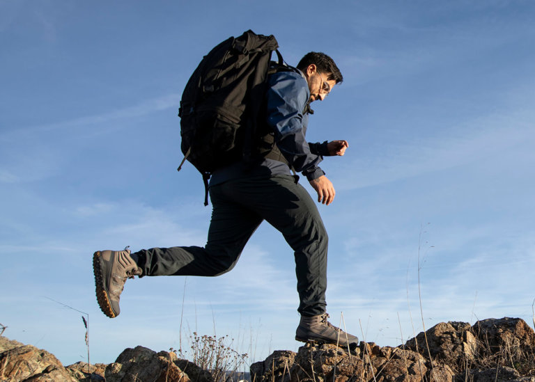 En man med Scrambler Mid II-stövlar hoppar från en klippa till en annan under en vandring