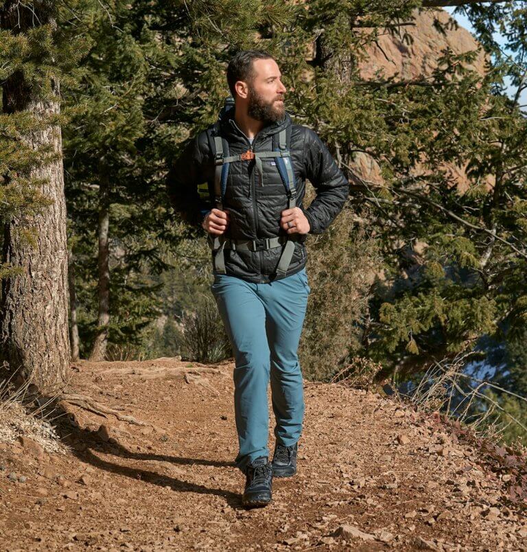 Un hombre haciendo senderismo por un camino de tierra un día fresco y despejado con sus botas Scrambler Mid II WP