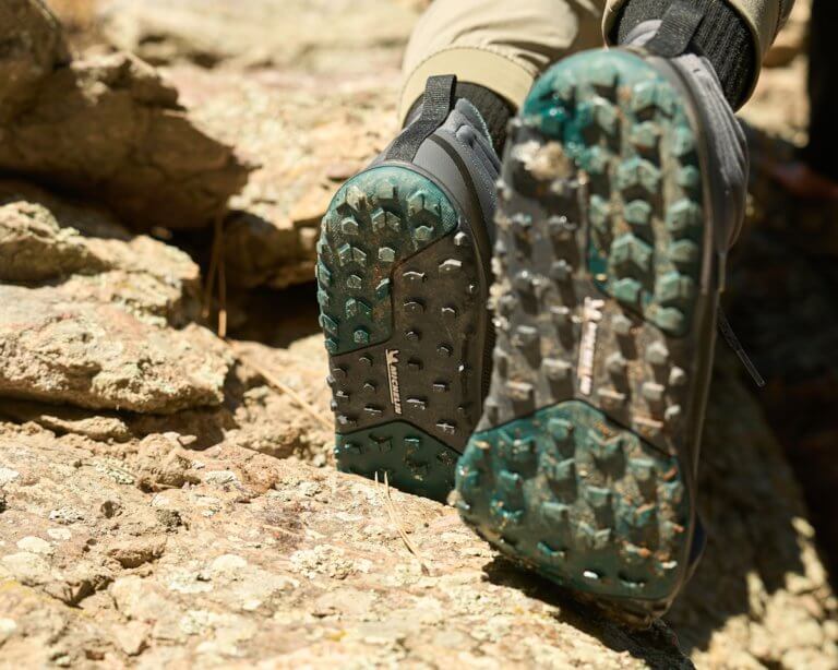 A close up shot of a woman wearing Scrambler Mid II WP boots showing off the flexible Michelin sole as she steps up